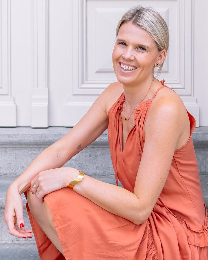 Sarah van club sol, op de trappen in haar terracotta jurk